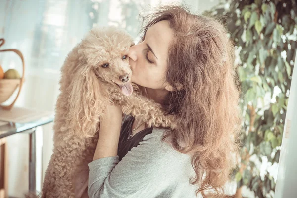 Unga kvinnor vilar med en hund hemma . — Stockfoto