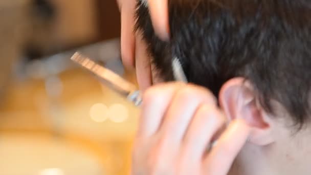 Peluquero corta el cabello del cliente con un cortador — Vídeo de stock