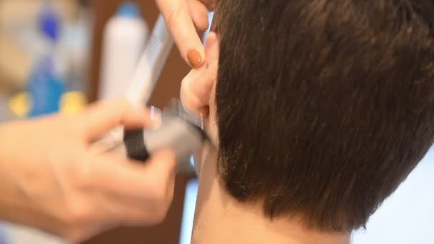 Peluquero corta el cabello del cliente con un cortador — Vídeo de stock