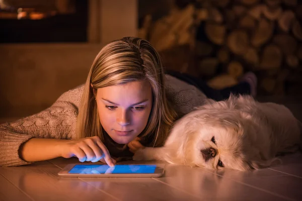 Genç kız evde bir köpekle dinleniyor ve tablet kullanıyor. . — Stok fotoğraf