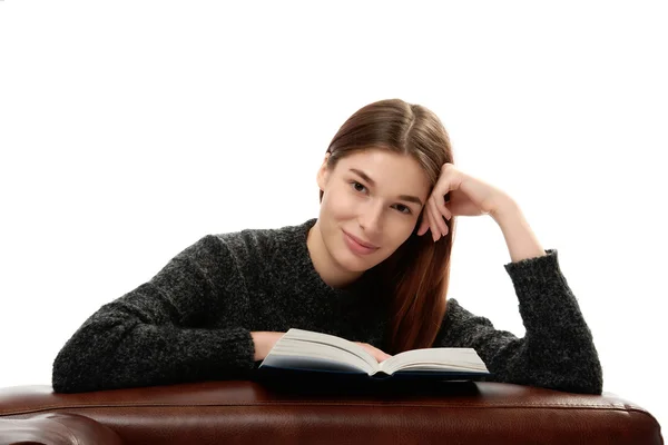 Jonge vrouw met boek leunend op lederen meubels — Stockfoto