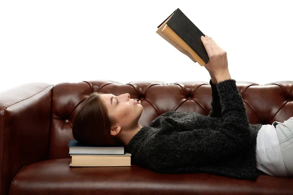 Mujer joven acostada en el sofá con libros bajo su cabeza —  Fotos de Stock