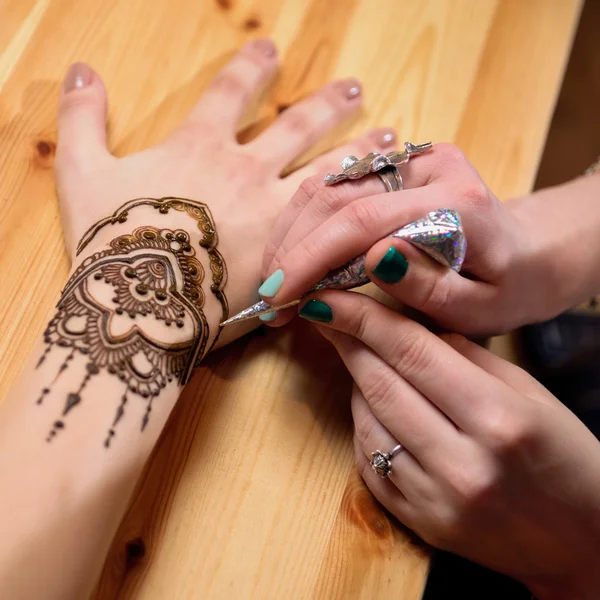 Young woman mehendi artist painting henna on the hand — Stock Photo, Image