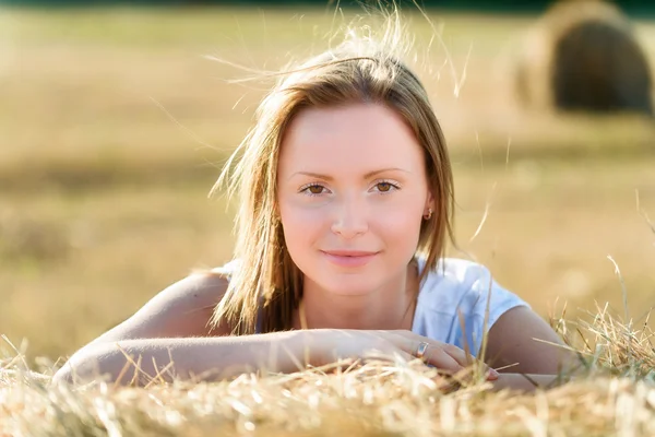 Portrait of a young woman who leans on a bale of hay — Stock Photo, Image