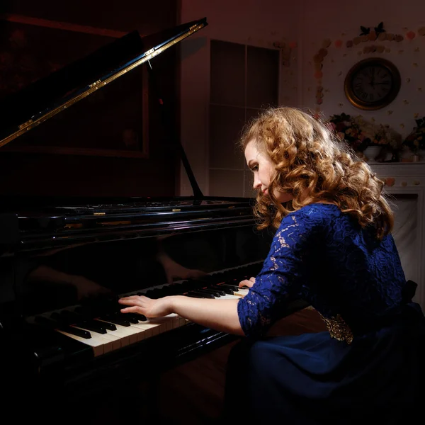 그랜드 피아노를 연주하는 젊은 여자 스톡 사진