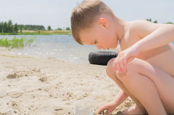 El muchacho es jugado por la arena la playa . — Foto de Stock