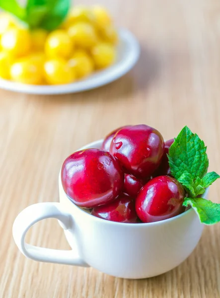 Em uma mesa há uma xícara com uma cereja doce . — Fotografia de Stock