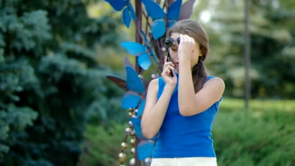 Tiener meisje praten over de telefoon in het park. — Stockvideo