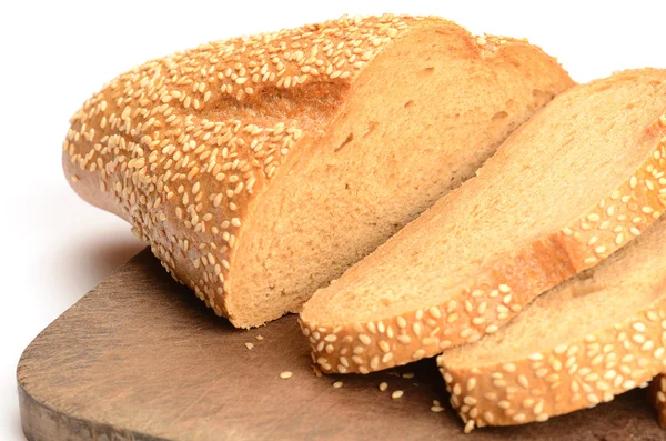 Pão fatiado numa tábua de corte isolada a branco — Fotografia de Stock