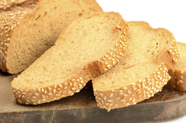 Pão fatiado numa tábua de corte isolada a branco — Fotografia de Stock