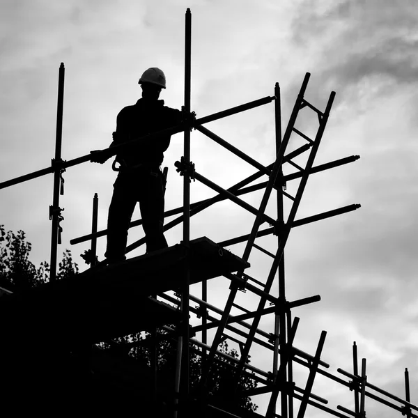 Silhouet bouwvakker op steigers bouwterrein — Stockfoto