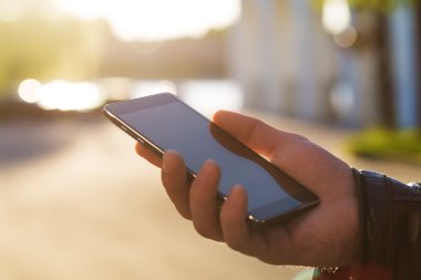 Adam cep telefonunu açık havada kullanıyor, kapat.