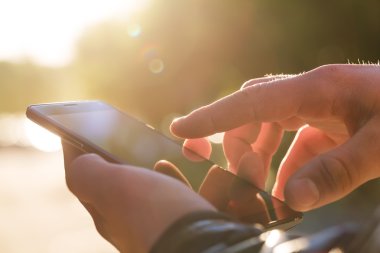 Adam cep telefonunu açık havada kullanıyor, kapat.