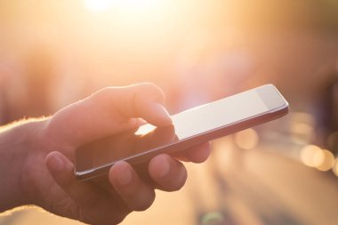 Adam cep telefonunu açık havada kullanıyor, kapat. Erkekler dışarıda cep telefonu kullanarak mesajlaşırken el ele tutuşuyorlar.