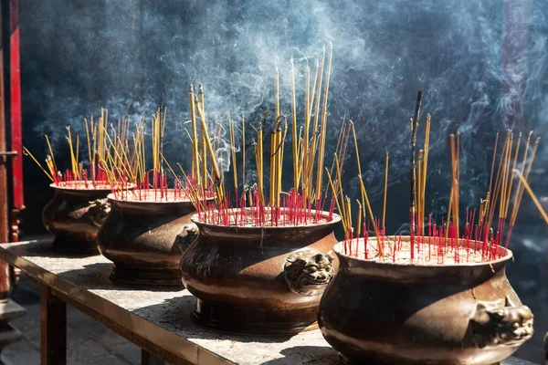 Burning red incense sticks in Chinese temple. Incense burning in a pot, blurred chinese temple background.