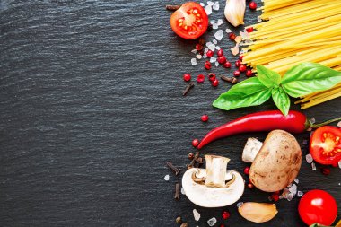 Domates, spagetti, baharat, sarımsak ve fesleğen yaprağı. İtalyan yemeği, sağlık veya yemek pişirme konsepti. Koyu arkaplanda yemek malzemeleri.