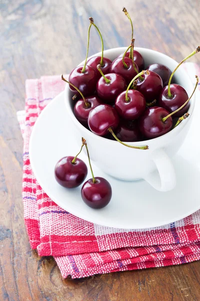 Cerises rouges fraîches dans un bol sur une table en bois — Photo