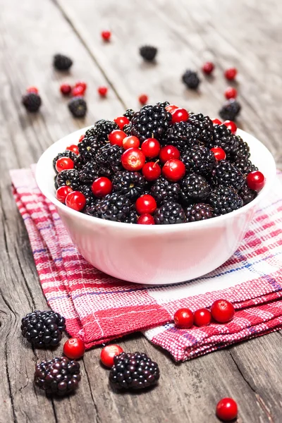 Brombeeren und Preiselbeeren in einer Schüssel auf einem Holztisch — Stockfoto