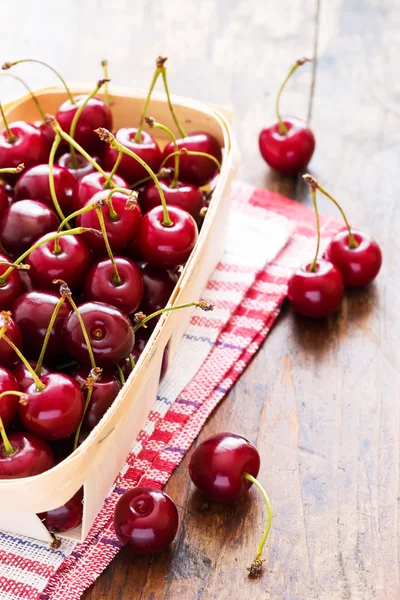 Cerises rouges fraîches dans un bol sur une table en bois — Photo