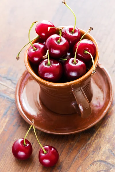 Cerezas rojas frescas en un tazón sobre una mesa de madera — Foto de Stock