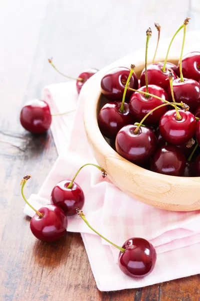 Cerezas rojas frescas en un tazón sobre una mesa de madera — Foto de Stock