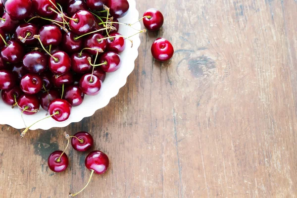 Fresh red cherries in bowl on a wooden table — Stock Photo, Image