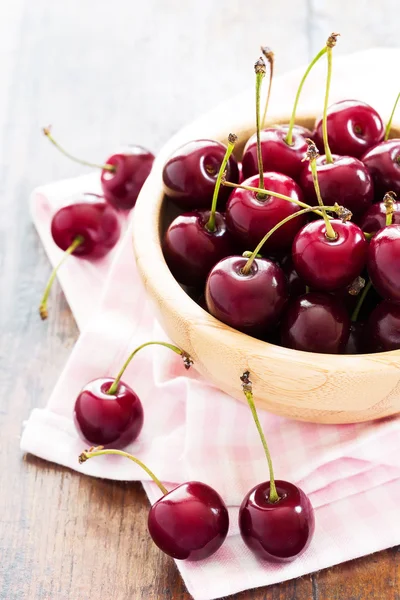 Cerezas rojas frescas en un tazón sobre una mesa de madera — Foto de Stock