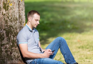 Parkta oturan ve bir akıllı telefon kullanarak adam 