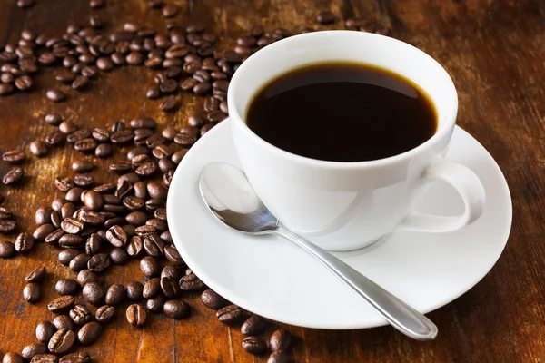 Kaffeetasse und Bohnen auf Holztisch — Stockfoto