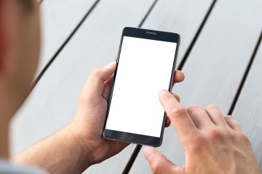 Adam akıllı cep telefonu üzerinde ahşap masa tutarak