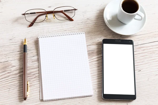 Notebook s brýlemi, tužka, chytrý telefon a šálek kávy na dřevěný stůl — Stock fotografie