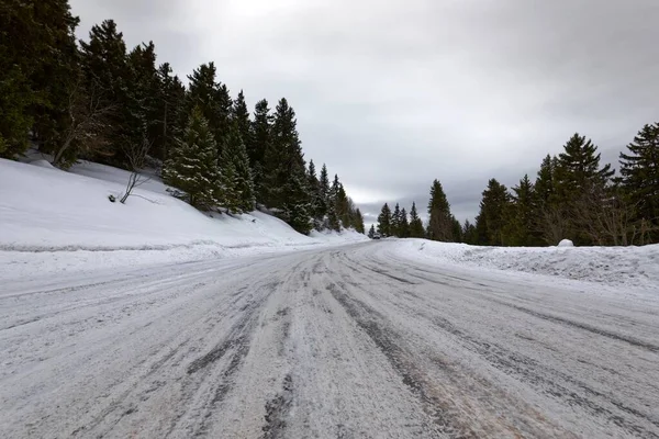 Strada di montagna innevata che attraversa le colline — Foto Stock