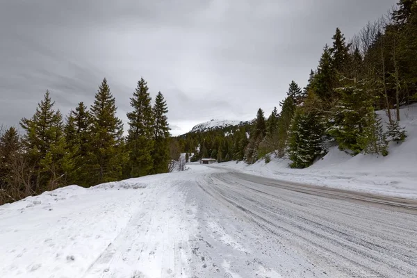 Nevado camino de montaña que se extiende a través de las colinas —  Fotos de Stock