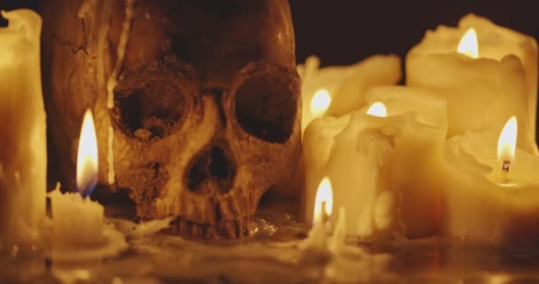 Svíčky a lidská lebka v temnotě detailní záběry — Stock video