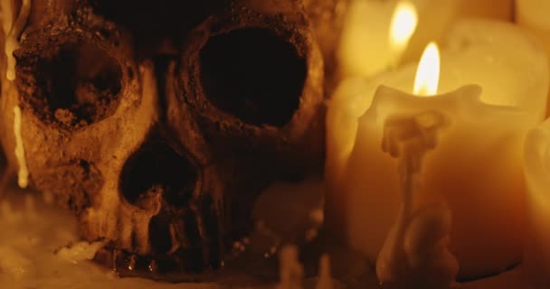 Velas e crânio humano na escuridão closeup imagens — Vídeo de Stock