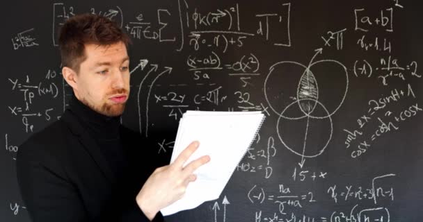 Teacher drawing mathematical formulas on black chalk board — Stock Video