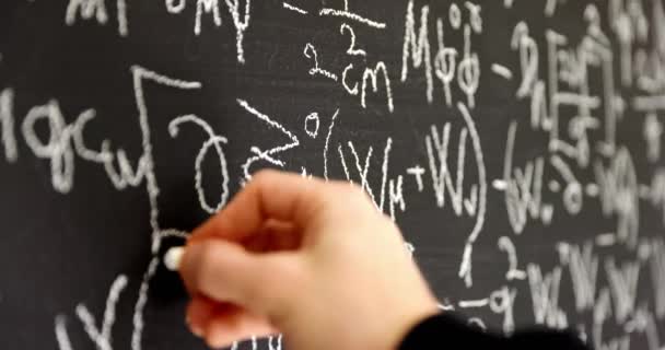 Écrire des formules mathématiques sur un tableau noir foncé — Video