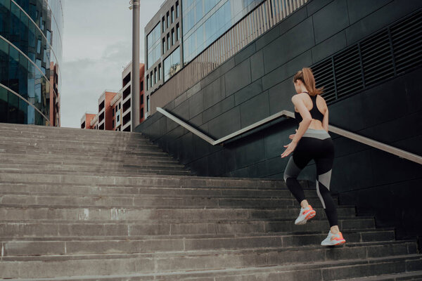 A young girl in a tracksuit runs up the stairs, in a business center