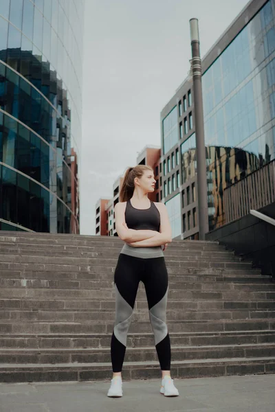 Jong sportmeisje deelde een plan, staat tegen de achtergrond van het gebouw — Stockfoto