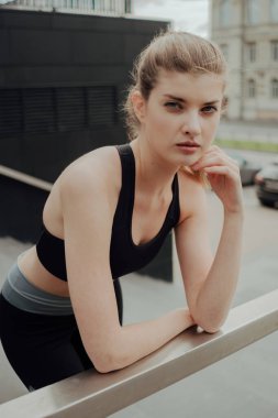 Eşofmanlı genç bir kız şehre karşı merdivenlerde duruyor.