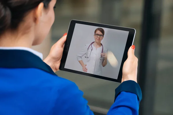 Blick von der Rückseite des Mädchens, das per Videolink mit einem Arzt spricht. lizenzfreie Stockbilder