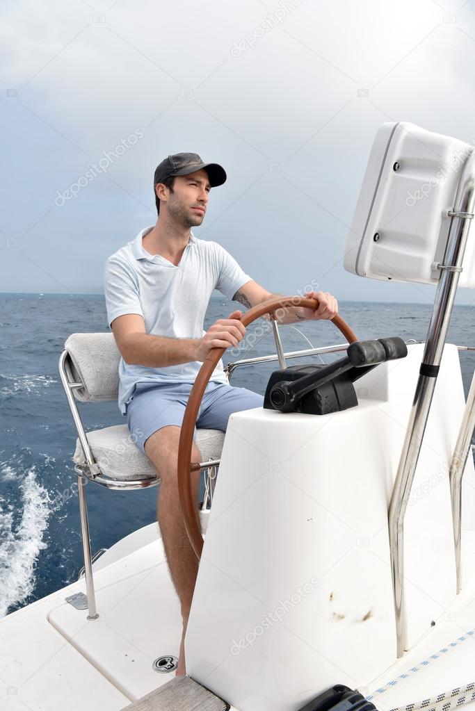 Skipper sitting at sailboat wheel