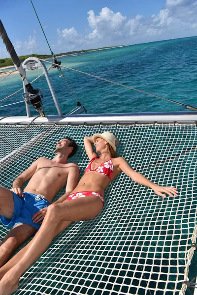 Couple suntanning on a catamaran net — Stock Photo, Image