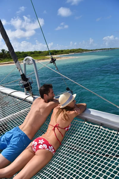 Couple suntanning on a catamaran net — Stock Photo, Image