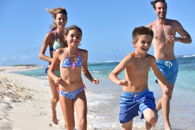 kumlu bir plaj üzerinde çalışan aile