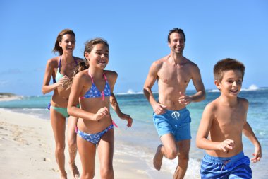 kumlu bir plaj üzerinde çalışan aile