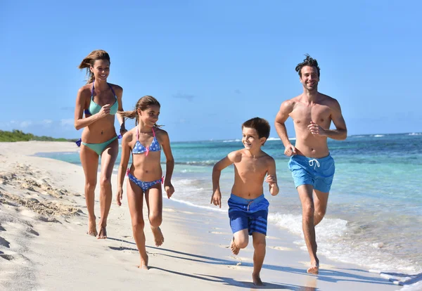 Família correndo em uma praia de areia — Fotografia de Stock