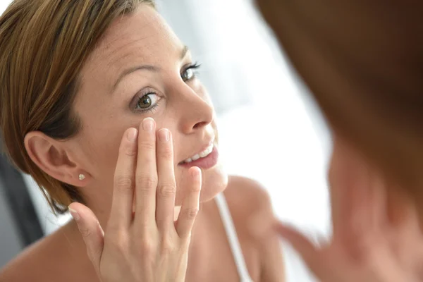 Frau trägt Gesichtscreme auf — Stockfoto