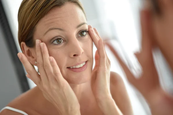 Frau trägt Gesichtscreme auf — Stockfoto