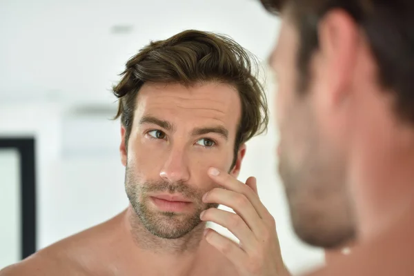 Hombre aplicando crema facial — Foto de Stock